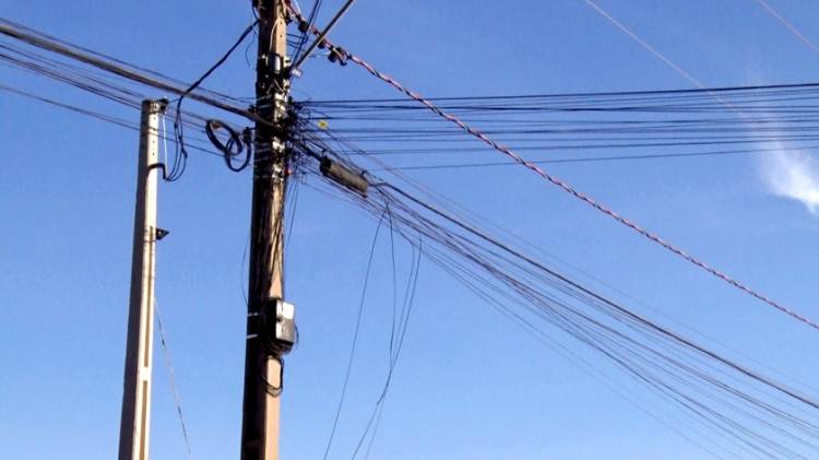 Sem fiscalização, postes e rede de energia viram emaranhados de fios pendurados